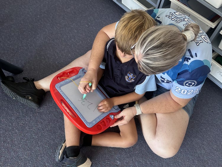 photo of a student and a staff member doing work togethor on a etch a sketch