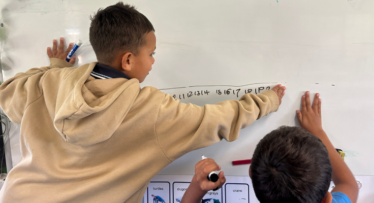 photo of 2 students writing a numberline on the whiteboard