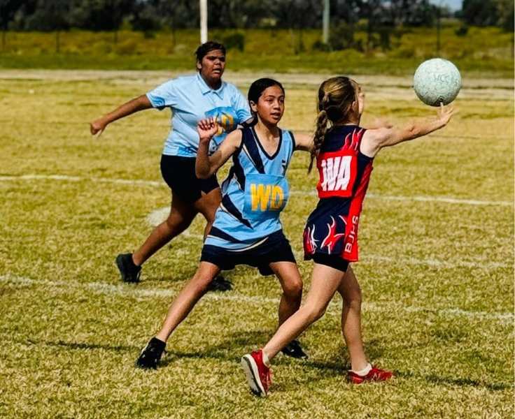 photo of 2 bourke public school students playing netball against an opposing school