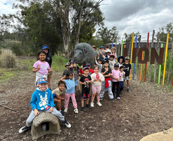 photo of infants students at the dubbo zoo posing infront of a lion statue